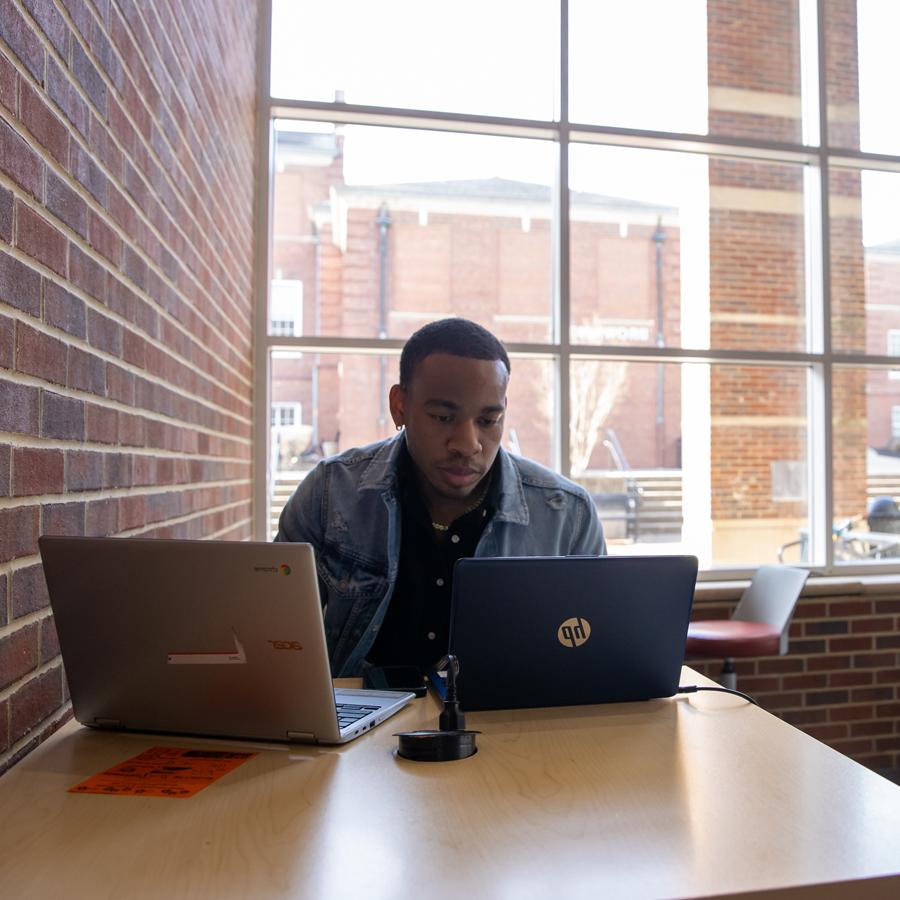 Student sitting in front of two laptops in the University Center