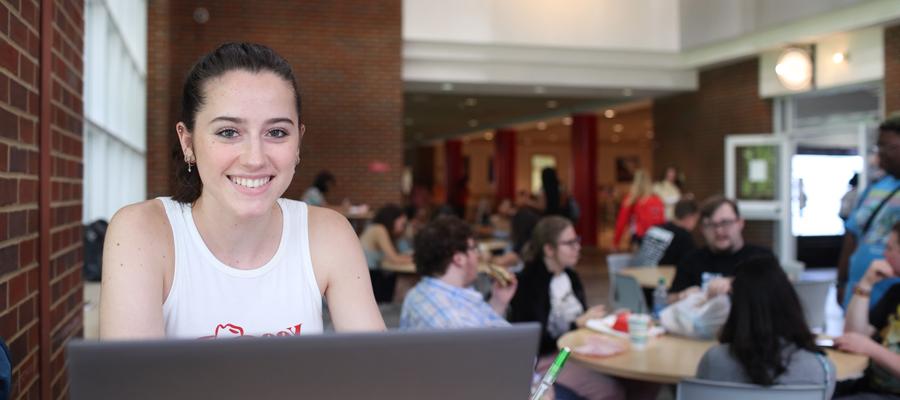 Student in the UC at their laptop with other students in the background